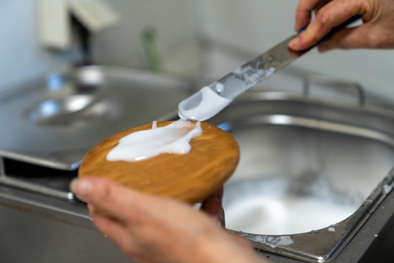 Kuchenboden wird in der Backstube von Hand mit Guss bestrichen